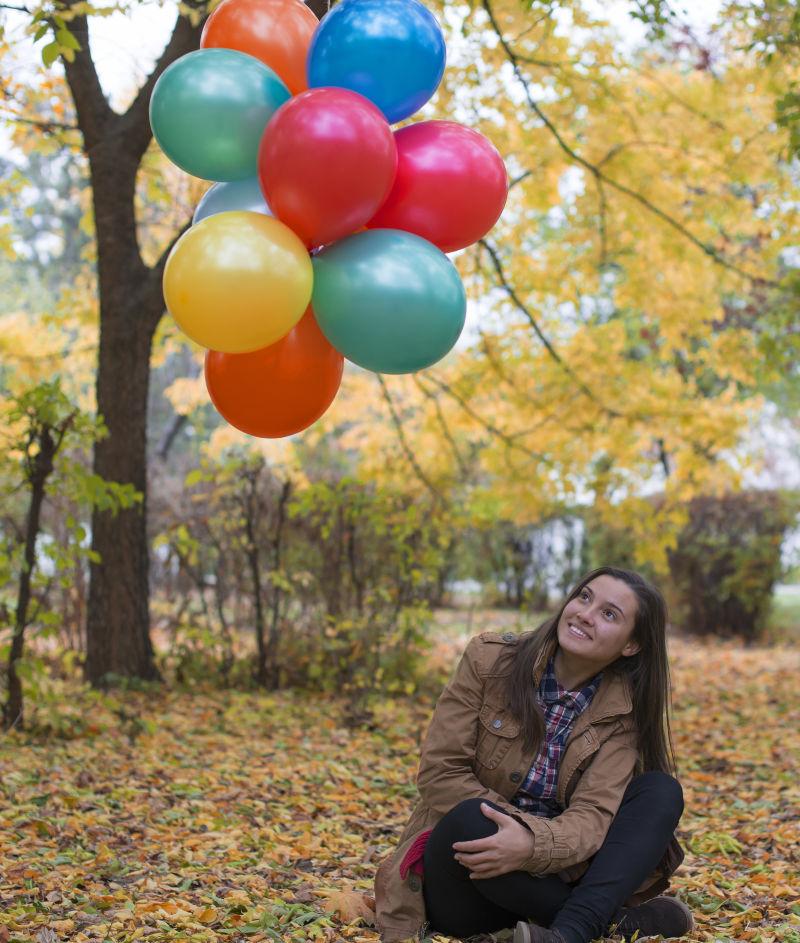 树林里的年轻的女孩和五彩气球