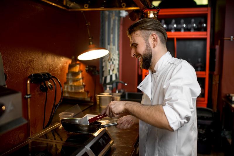  暗色有灯的背景下正在烹饪的厨师