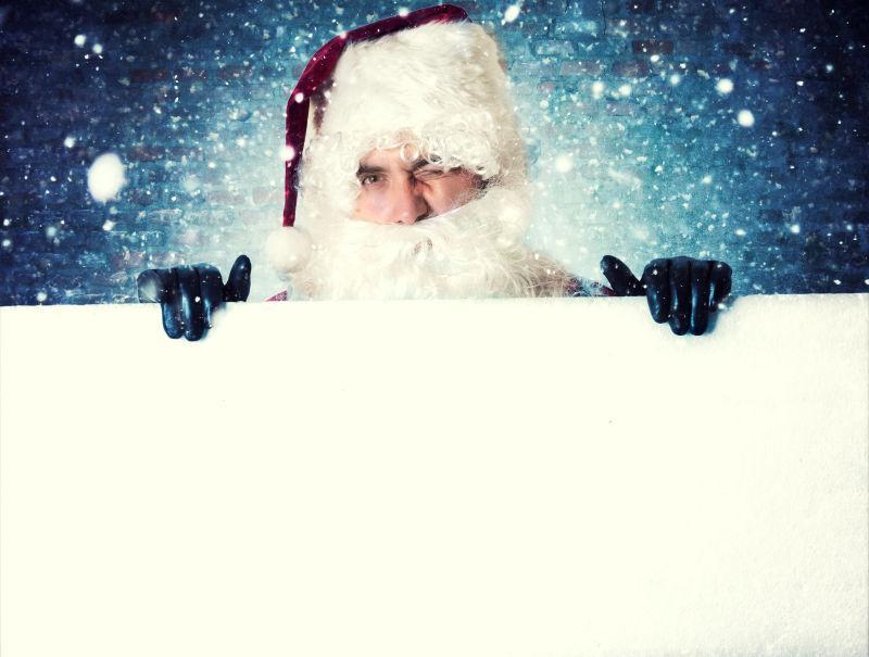 蓝色星空背景下拿着白色板子的圣诞老人