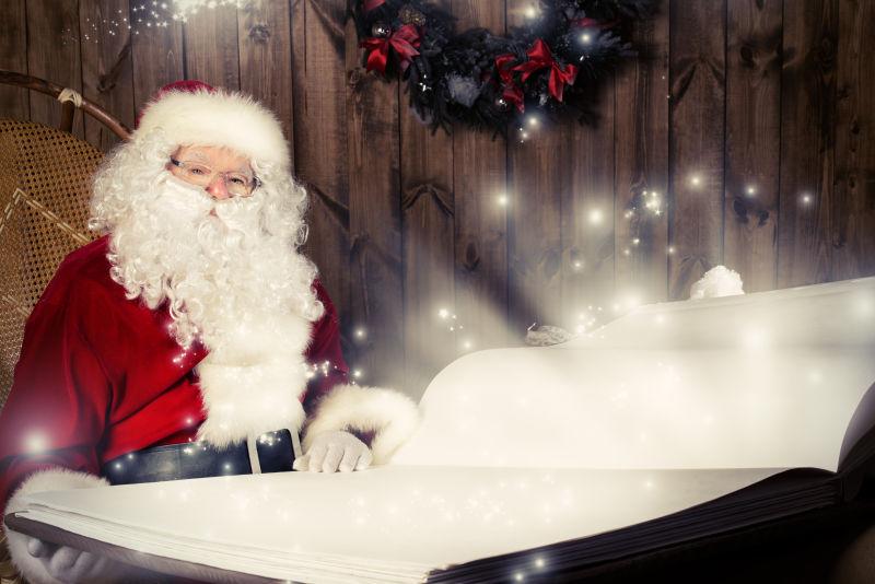 木制背景下翻看大圣诞书的圣诞老人