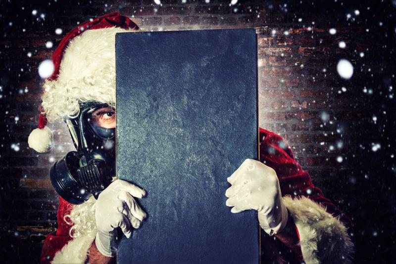 褐色木制背景下戴着面具拿着小黑板的圣诞老人