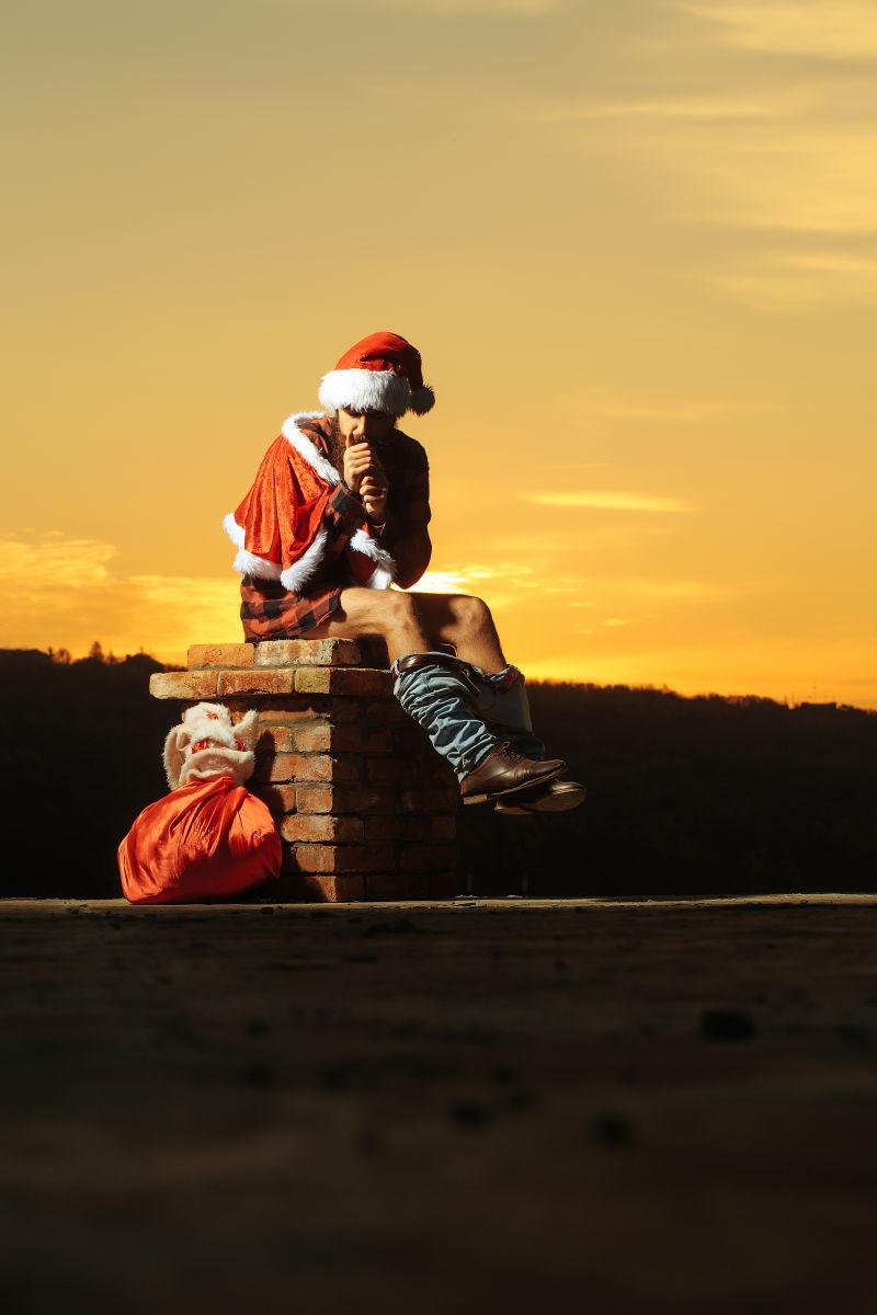年轻的留胡须的坏男人圣诞老人在烟囱上拉大便