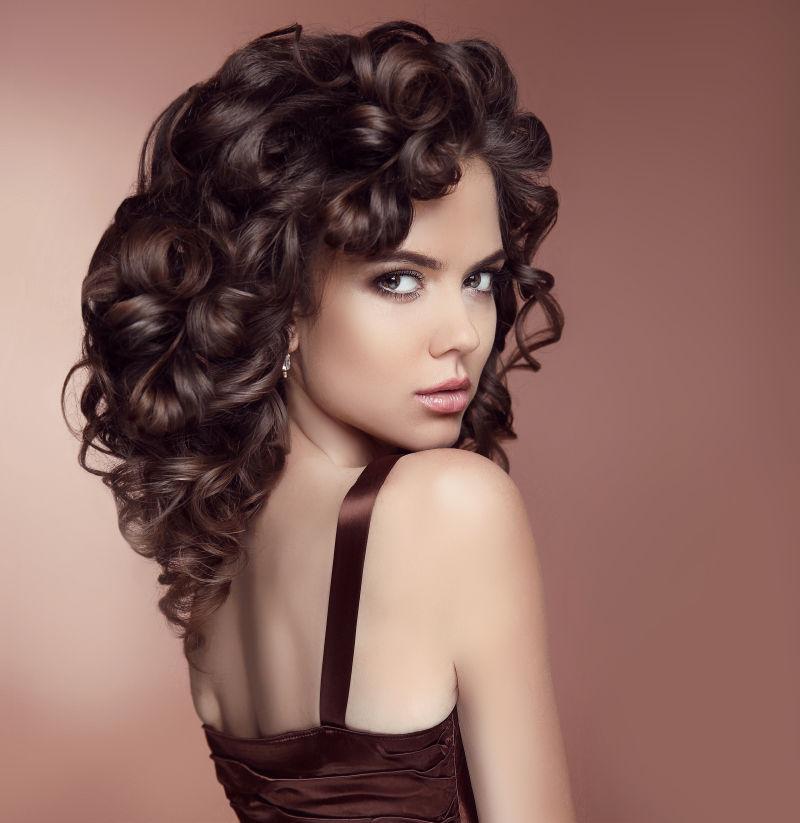 健康的发亮发型的迷人的女孩孤立在巧克力色的背景