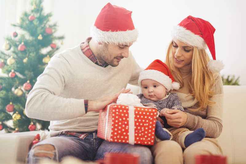 一家三口带着圣诞帽在看礼物