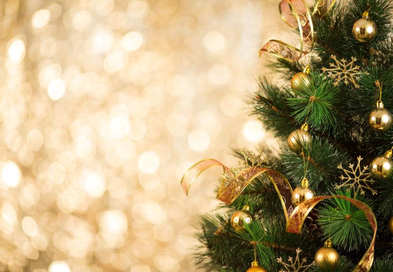 金色闪光背景下的挂着金色铃铛的圣诞树