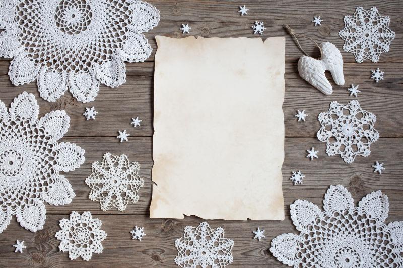 木制背景下的花边雪花和空白纸