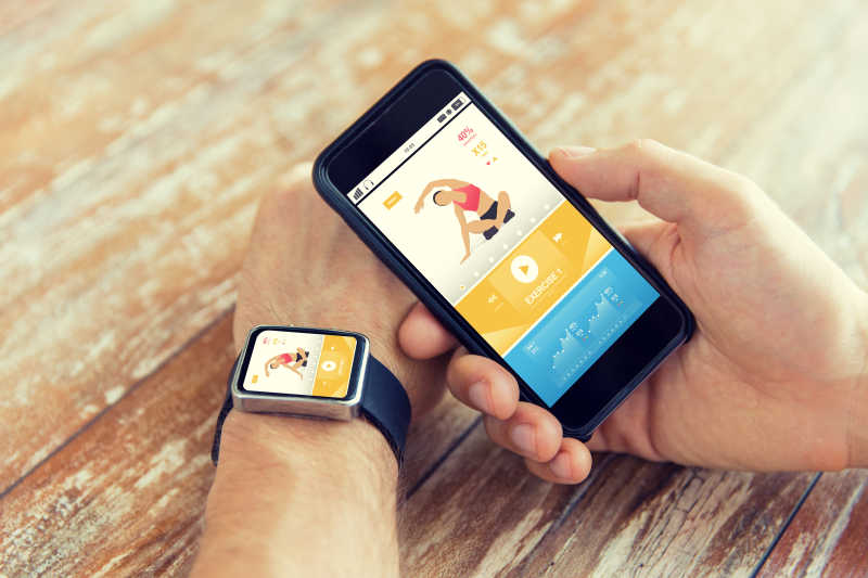 手持智能手机和手表以及屏幕上的体育应用