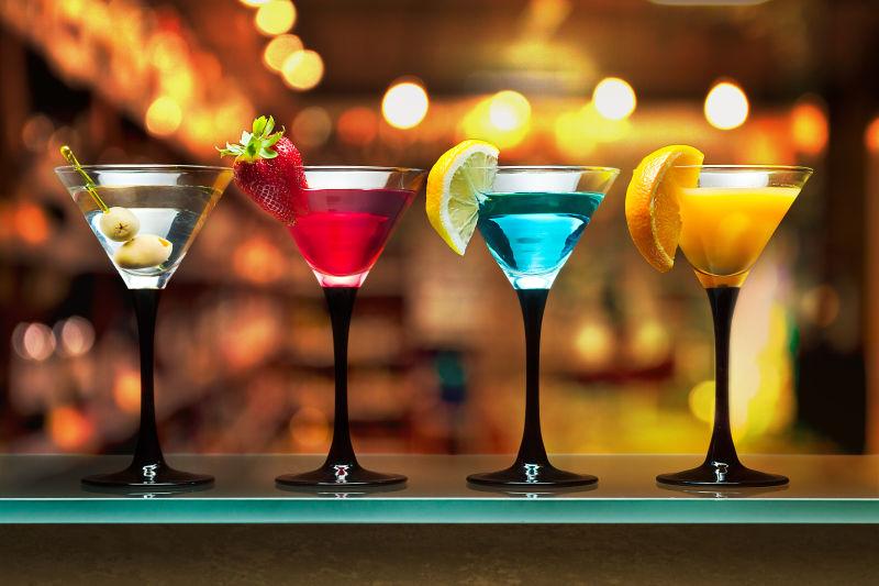 金色灯光背景下的四杯不同颜色的鸡尾酒