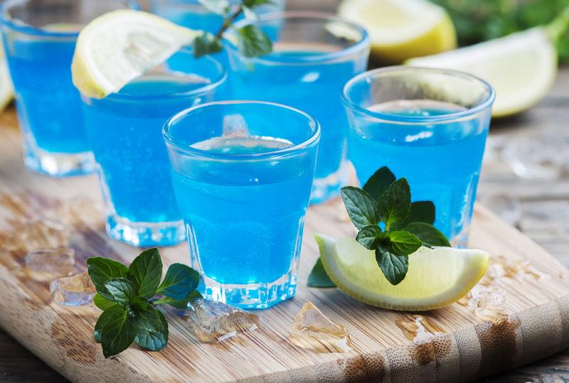 木板上的带有柠檬和薄荷的蓝色鸡尾酒