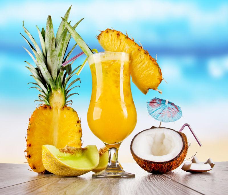 蓝色大海背景下木桌上的水果鸡尾酒