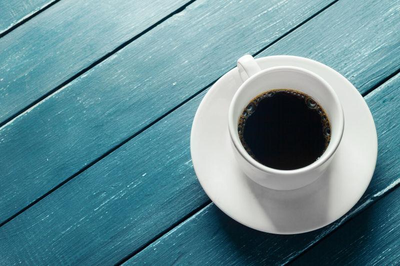 蓝色木桌上的咖啡杯