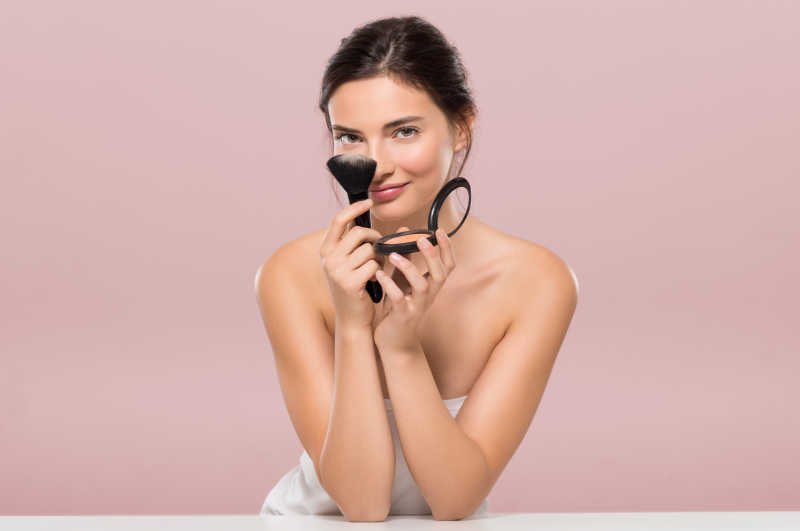 拿着粉盒和刷子的女子