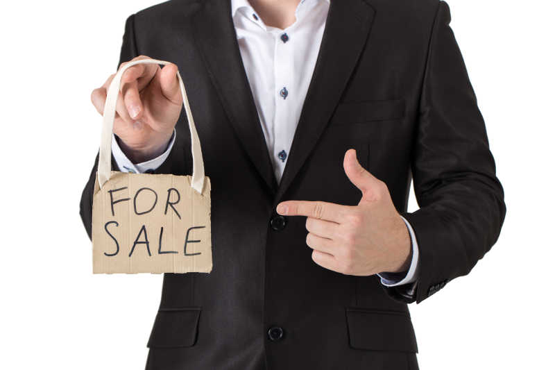 男人手里的牌子写着FOR SALE