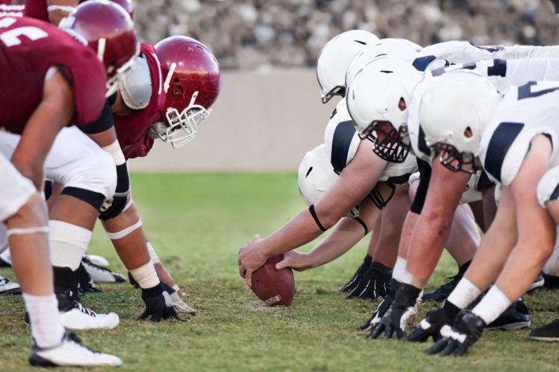 绿色运动场上的两队装备齐全的美式足球队