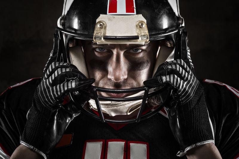 黑色背景下装备齐全的橄榄球运动员