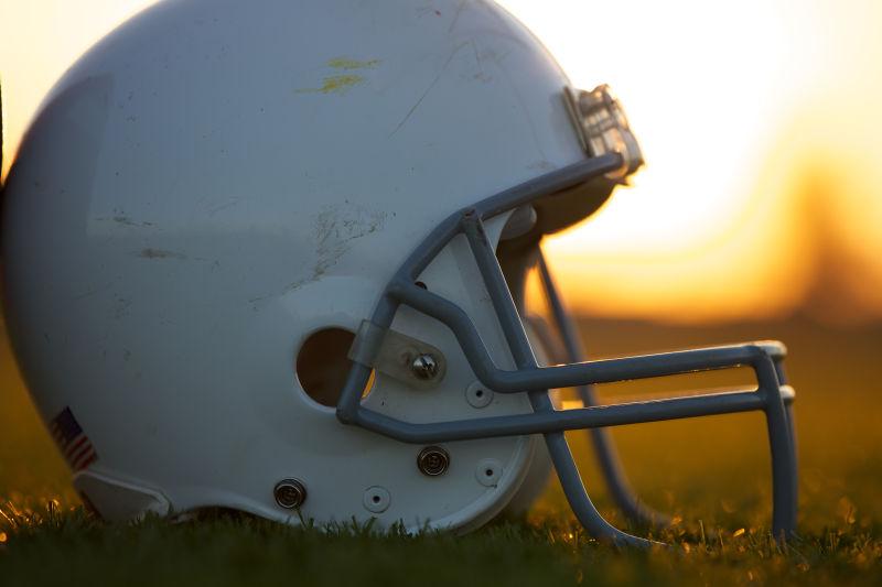 夕阳下草地上的美式橄榄球头盔