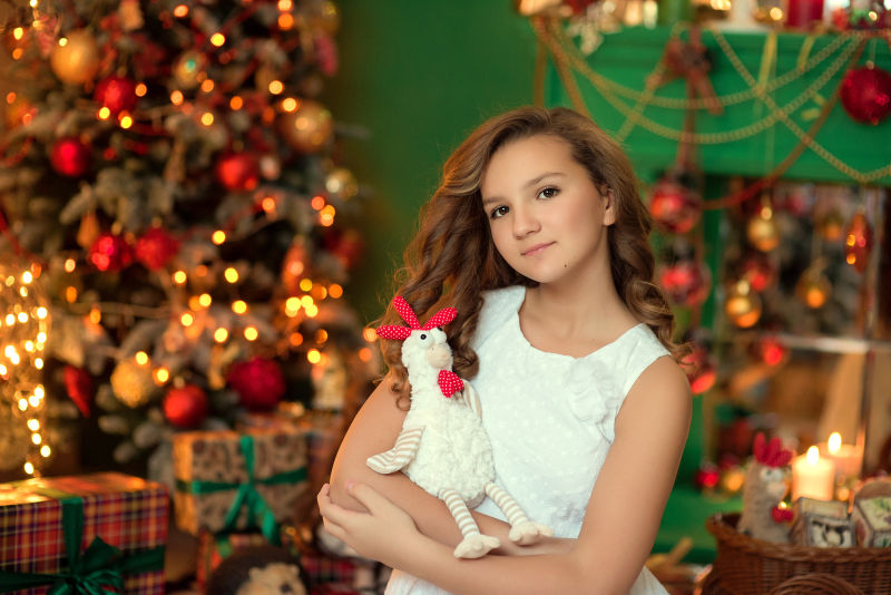 圣诞背景下抱着布偶的小女孩