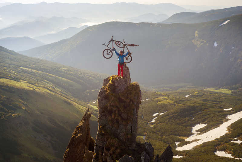 黑山山脉山峰上的举着自行车的极限运动员