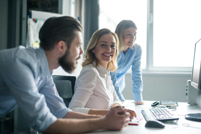 电脑桌前的两个美女和一个男人