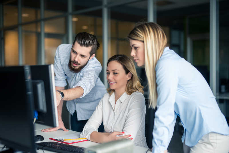 帅哥在给两个美女同事讲解