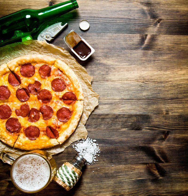 木桌上的香肠比萨饼和啤酒