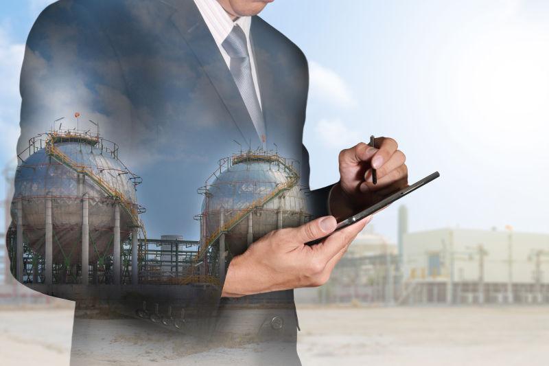 使用平板的商人和能源炼油厂的双重曝光