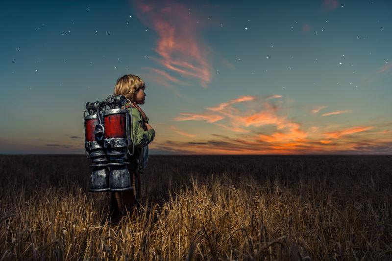 日落下背喷气式飞行器的男孩